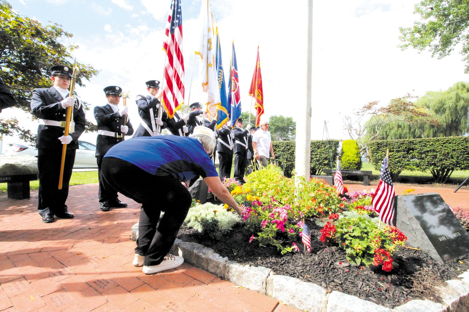 FOR THE FALLEN: As the names of eight Rhode Islanders killed in the September 11 attacks were read aloud, an attendee places flowers to honor those lost as an honor guard stands by.